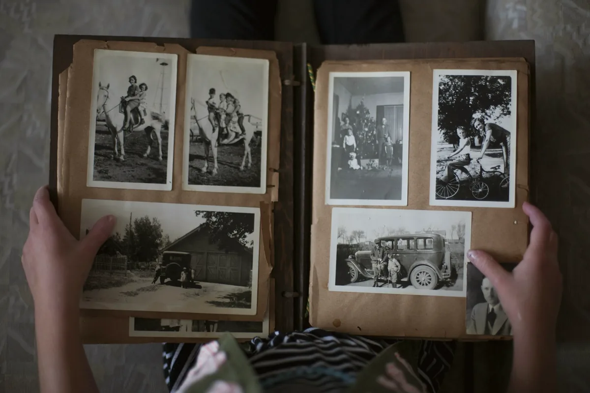 Mains tournant les pages d’un album de famille aux photographies en noir et blanc